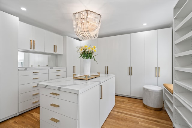 walk in closet with light wood-style flooring and a notable chandelier