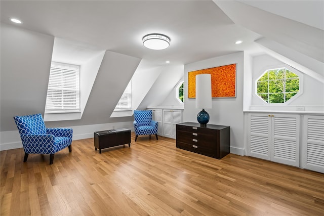 living area with baseboards, vaulted ceiling, and wood finished floors