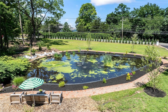 view of pool with a garden pond and a lawn