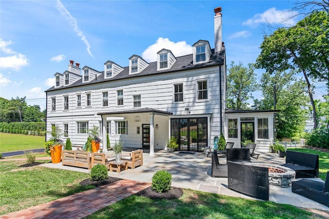 back of property with a yard, an outdoor living space with a fire pit, a patio, and a chimney