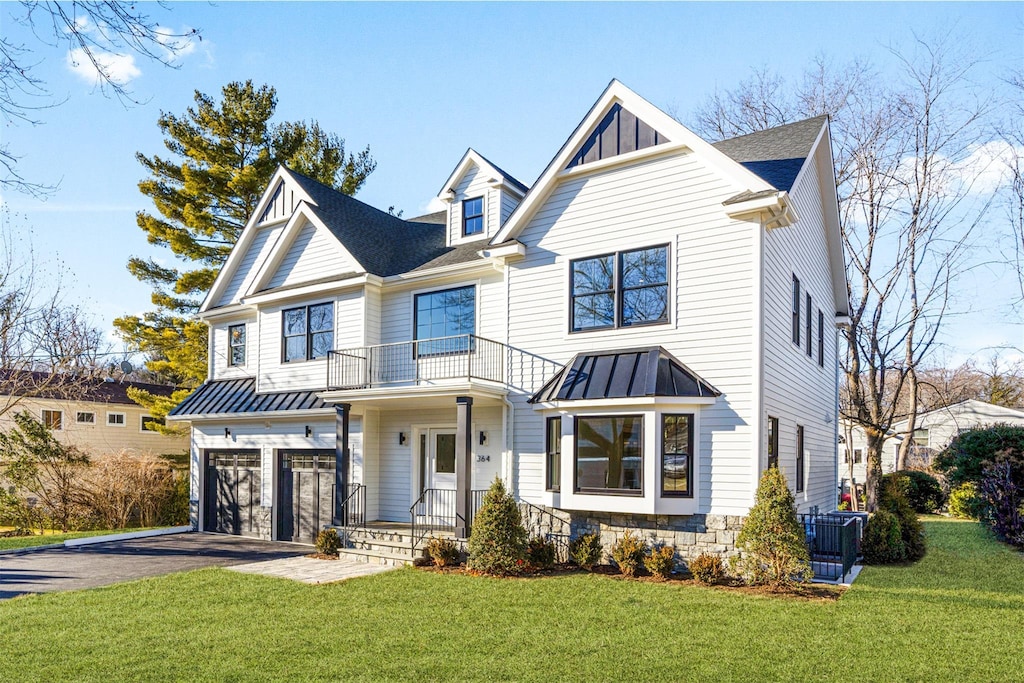 view of front of house featuring a garage, a balcony, and a front yard