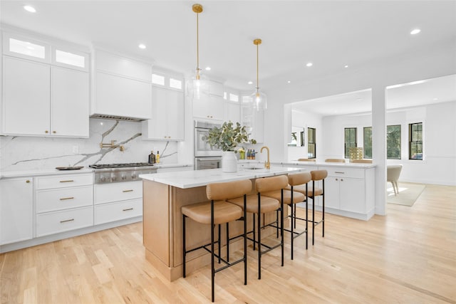 kitchen with white cabinets, an island with sink, appliances with stainless steel finishes, and a breakfast bar