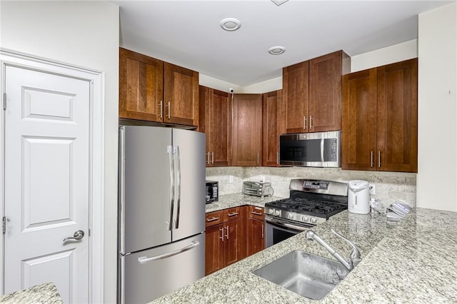 kitchen featuring sink, appliances with stainless steel finishes, tasteful backsplash, and light stone countertops