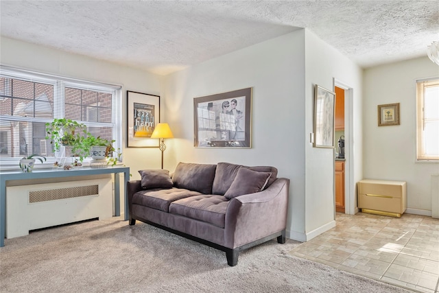 living room with radiator, light carpet, baseboards, and a textured ceiling