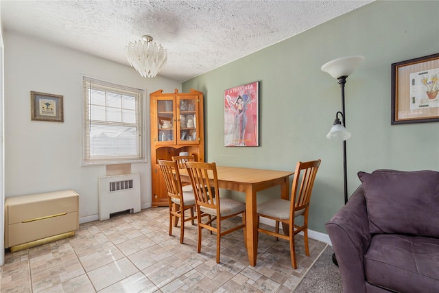 dining room with a textured ceiling, radiator heating unit, and baseboards