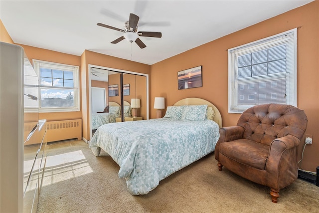 bedroom with a closet, ceiling fan, radiator heating unit, and carpet flooring