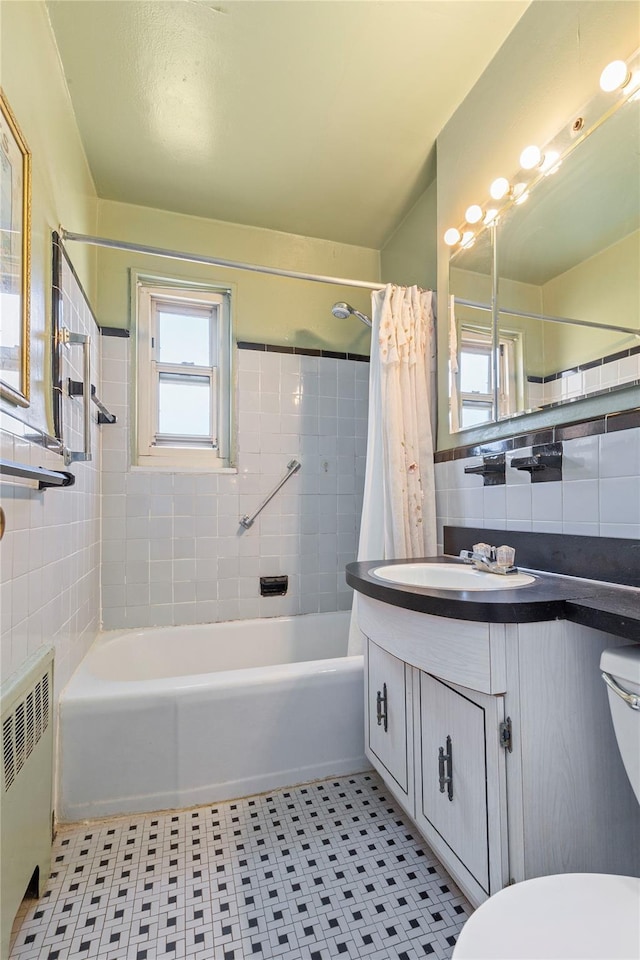 full bath with tile walls, radiator, toilet, shower / tub combo, and vanity