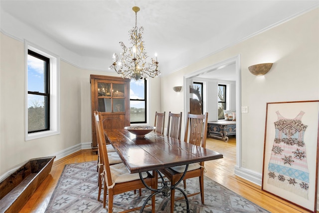 dining space with wood finished floors, a wealth of natural light, and a notable chandelier