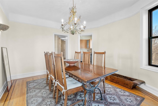 dining space with a notable chandelier, wood-type flooring, and baseboards