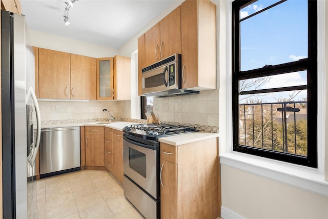 kitchen featuring light tile patterned flooring, stainless steel appliances, light countertops, backsplash, and glass insert cabinets