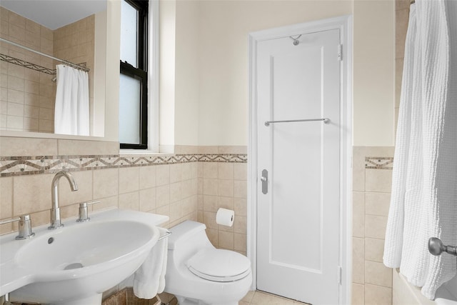 bathroom with toilet, shower / bathtub combination with curtain, tile walls, and a sink