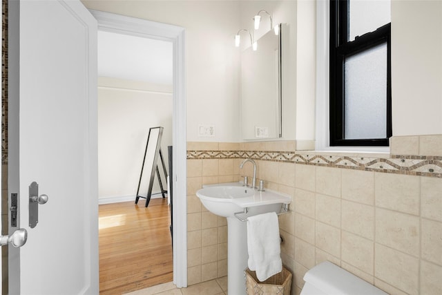 bathroom featuring toilet, tile patterned floors, tile walls, and wainscoting