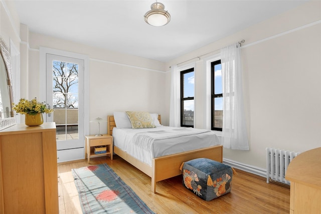 bedroom with radiator heating unit and light wood-type flooring