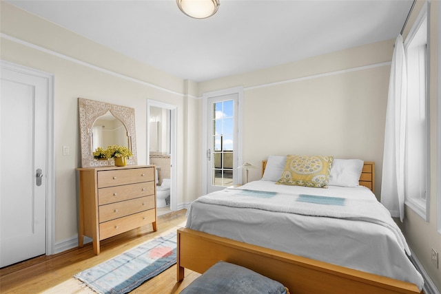 bedroom featuring ensuite bathroom, light wood-style flooring, and baseboards