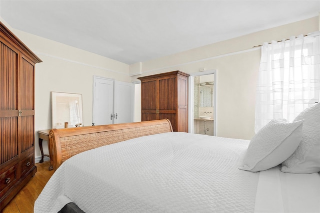 bedroom with ensuite bath, multiple windows, and wood finished floors