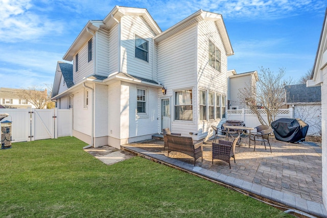 rear view of house featuring a lawn, a patio area, a fenced backyard, and a gate