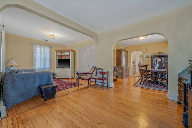 living area featuring arched walkways and light wood-style flooring