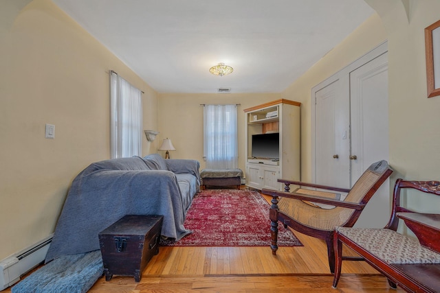 living area with a baseboard radiator, visible vents, and wood finished floors