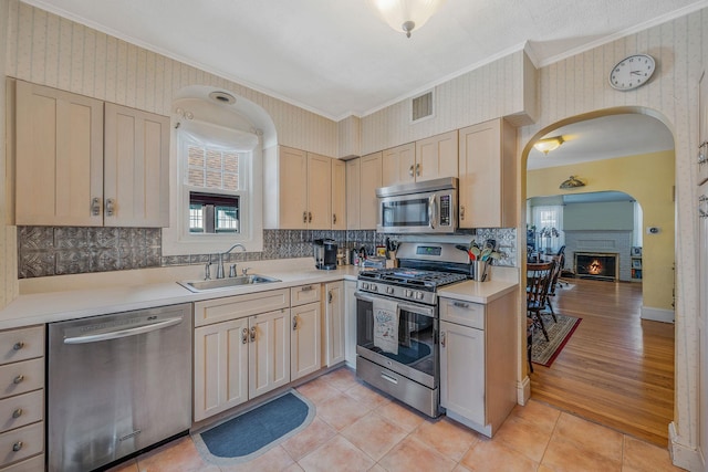 kitchen with stainless steel appliances, a sink, visible vents, and wallpapered walls