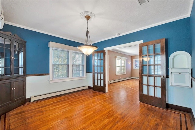 unfurnished dining area with ornamental molding, french doors, baseboard heating, and wood finished floors