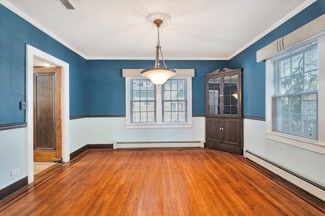 unfurnished room with a baseboard radiator, wood finished floors, visible vents, and crown molding