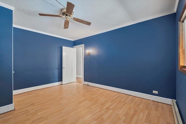 spare room featuring baseboards, crown molding, baseboard heating, and wood finished floors