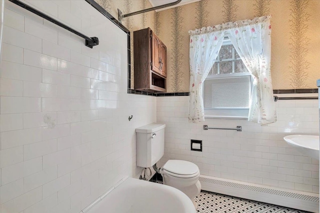 full bathroom with a wainscoted wall, tile walls, toilet, baseboard heating, and wallpapered walls