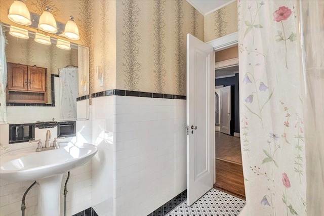 bathroom with wainscoting, tile walls, and wallpapered walls