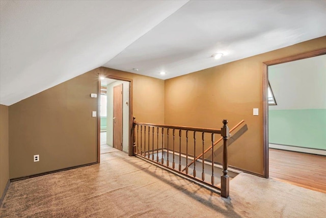 bonus room with a baseboard heating unit, lofted ceiling, and light carpet