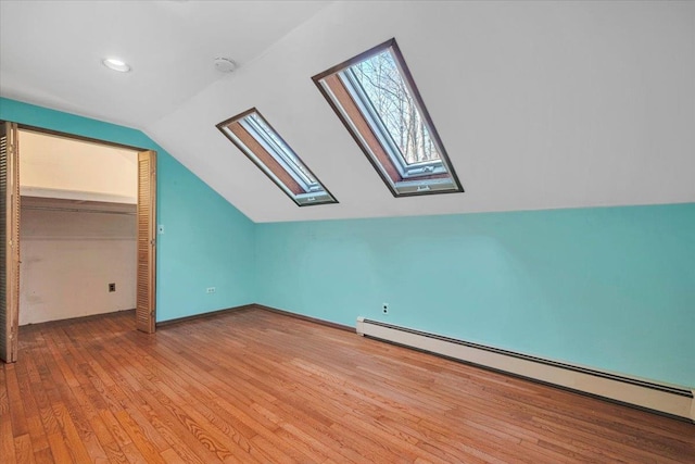 bonus room with light wood finished floors, baseboard heating, and lofted ceiling with skylight