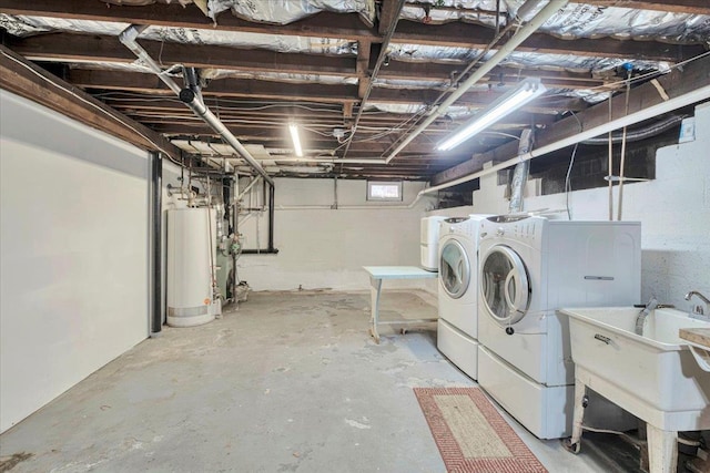 below grade area featuring a sink, gas water heater, and independent washer and dryer