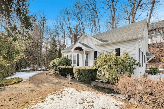 exterior space with a chimney and roof with shingles