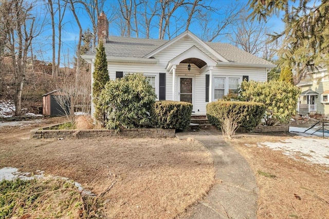 bungalow with roof with shingles and a chimney