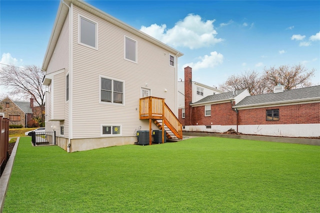 back of property with central air condition unit and a lawn