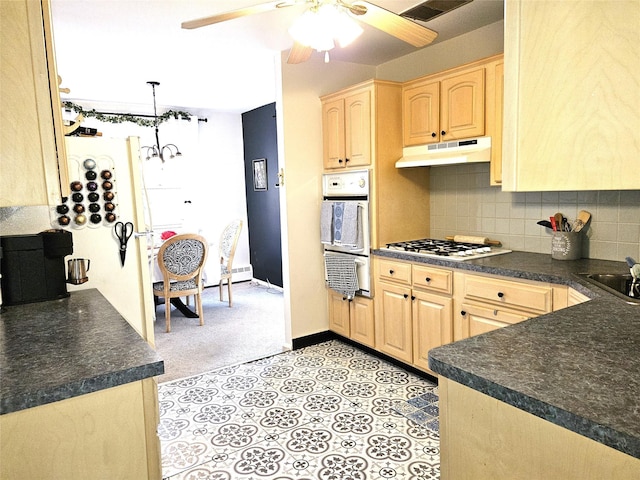 kitchen featuring dark countertops, tasteful backsplash, white gas cooktop, under cabinet range hood, and light brown cabinetry