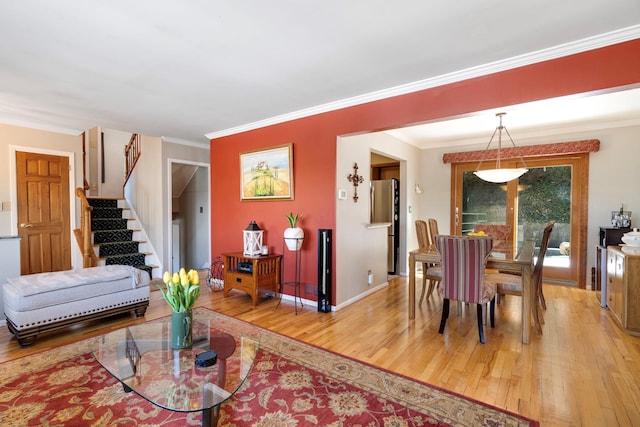 living room with stairs, ornamental molding, wood finished floors, and baseboards