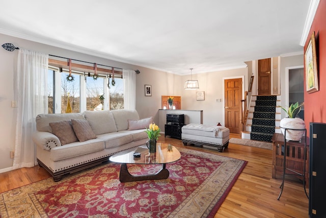 living area featuring light wood finished floors, baseboards, stairway, and ornamental molding