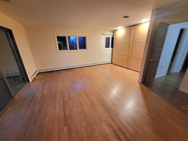 unfurnished room with hardwood / wood-style flooring and a baseboard radiator