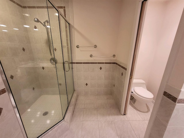 bathroom featuring tile patterned floors, toilet, tile walls, and walk in shower