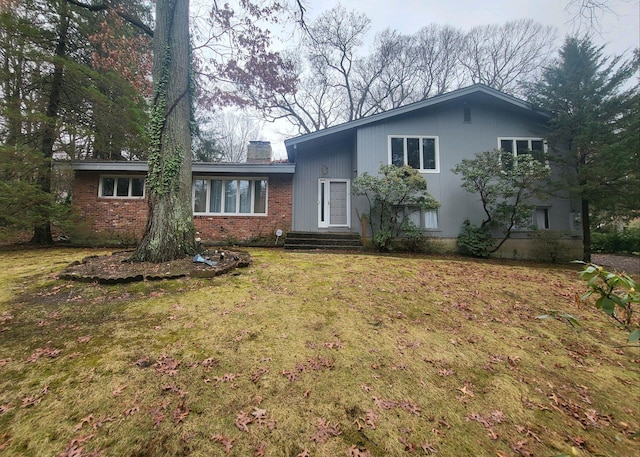 tri-level home with a front yard, brick siding, and a chimney