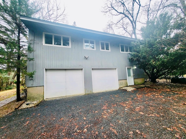 exterior space with an attached garage and gravel driveway