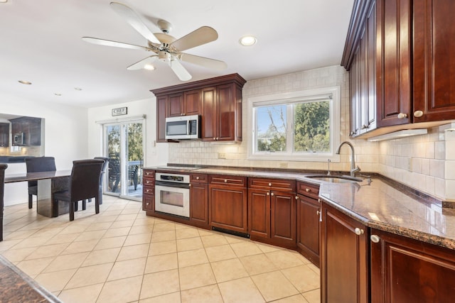 kitchen with stainless steel appliances, a sink, decorative backsplash, and dark brown cabinets