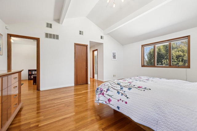 bedroom with vaulted ceiling with beams, light wood finished floors, and visible vents