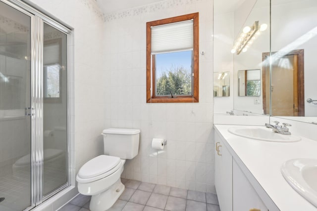 full bathroom with toilet, a sink, tile walls, and tile patterned floors