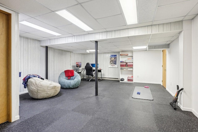 finished basement featuring a paneled ceiling and baseboards