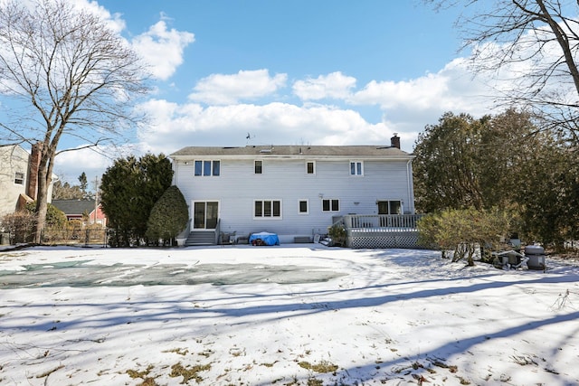 snow covered property with a chimney and a wooden deck