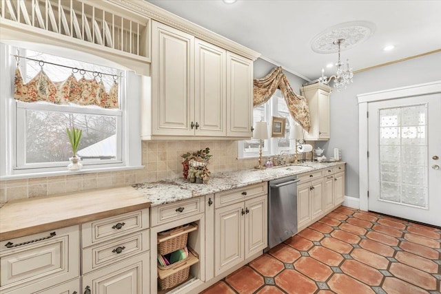 kitchen featuring cream cabinets, decorative light fixtures, sink, tasteful backsplash, and dishwasher