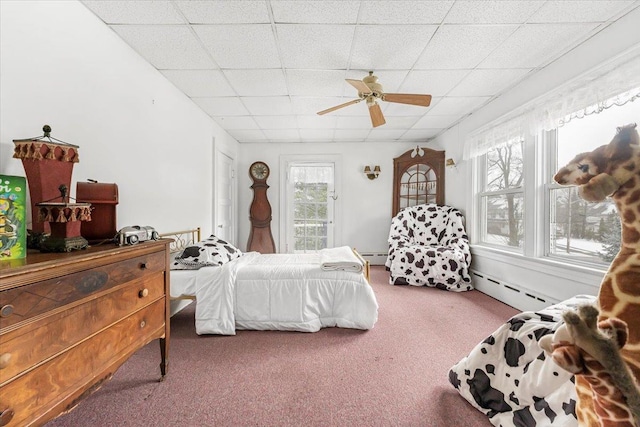 carpeted bedroom with a baseboard heating unit, multiple windows, and a drop ceiling