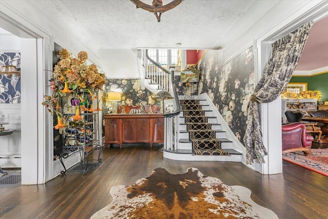 entrance foyer featuring a textured ceiling, ornamental molding, and dark hardwood / wood-style flooring