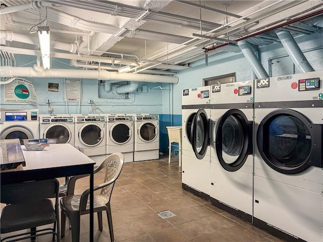 clothes washing area with dark tile patterned flooring and washer and clothes dryer